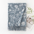 Grey-blue faux cashmere scarf with white floral print and tassel edges, folded neatly - Blue Background White Floral