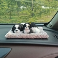 Lifelike black and white toy dogs lying on a grey plush mat on a car dashboard - Border Collie Parent-Child Sitting Set