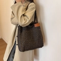 Grande borsa tote leopardata con tasca esterna indossata da una modella in trench - Nero
