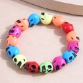 Bracciale con perline a teschio colorate in resina su uno sfondo di legno naturale - Colorato