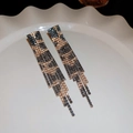 Makroaufnahme von langen Leopard-Quastenohrringen mit glänzenden Strasssteinen auf Dekor - Quasten Ohrringe mit Leopardenmuster und Strass / Gold