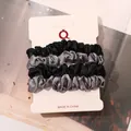 Detail of 4-pack satin hair scrunchies in black and grey on a display card - Black and Blue Gray