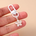 Close-up of a white cherry blossom keychain with a spring clasp held in hand - White Flower