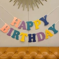 Colorful macaron Happy Birthday letter banner with gold foil hanging on a wall - Colorful Pearlescent Macaron Birthday Banner