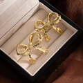 Elegant gold bow-shaped stud earrings with a high-polished metallic finish on a jewelry box - Gold Bowknot