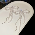 Dettaglio di orecchini a fiocco con perle pendenti e nappe argentate su piatto bianco - Orecchini Fiocco con Nappa / Perno in argento-Bianco