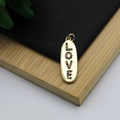 Macro detail of gold 18K plated oval pendant with colorful zircon stones spelling LOVE - LOVE Letter Oval Colorful Style