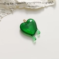 Close-up of a translucent green melting heart pendant with a gold ring attachment - Light Green