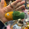 Close-up of a handmade yellow and green wool felt fish keychain with a metal ring - Green