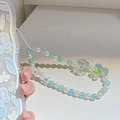 Detail of blue ice-textured beads and acrylic flower charm on a phone strap - Blue Beaded Cord