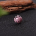 Pink natural gemstone sphere with black textures on a rustic wooden background - Rhodonite with Black Lines