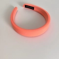 Close-up of coral orange padded sponge headband with a black handmade woven label - Orange
