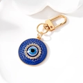Detail eines herzförmigen Evil-Eye-Schlüsselanhängers mit Emaille und Glitzersteinen - Goldene Rundes Dunkelblaues Auge