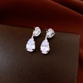 Detailed view of silver zircon drop earrings on brown leather with silk background - Silver (Silver Earring Post)