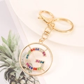 Detailed macro view of golden metal keychain featuring a colorful rhinestone letter G charm - Letter G