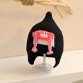Detail of baby winter knit hat with cute pink cartoon face and braided tassels - One Size (Toddler) / Black