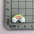 Macro-opname van een 2 cm mini-regenboog harsbedeltje op een metrische schaalverdeling - Geel Roze Groen