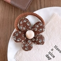 Close-up of floral fabric hair tie with brown petal patterns and a plush center ball - Floral Print Hair Tie