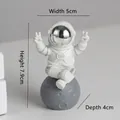 White resin astronaut figurine sitting on moon base with silver mask and V-sign gesture - Small Silver-edged Model C