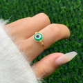 Detail of handmade wire-wrapped gold ring featuring a green evil eye bead charm - Style 1 Gold+Green (0581)