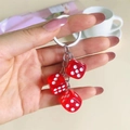 Close-up of metal keychain with three transparent red resin dice pendants in a lifestyle setting - Red