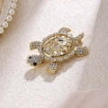 Fashionable gold turtle brooch with faceted crystals and rhinestones on a textured surface - White