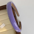 Detalle de diadema morada brillante con forro de terciopelo suave sobre madera - Morado