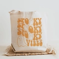 Cute Spooky Vibes Halloween canvas tote bag with ghost print on a straw mat - Spooky Vibes Retro Orange Text