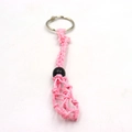 Close-up of pink handmade macrame cord keychain with black bead on a white surface - Keychain / Pink