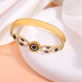 Macro detail of gold titanium steel bracelet with evil eye design and rhinestones - Retro Circle Drip Oil Bangle