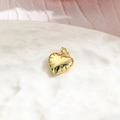 Macro shot of gold heart pendant with radial texture on a ceramic plate detail - Heart / Gold