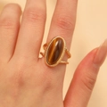 Detailed view of vintage gold-plated open ring with oval tiger eye stone on a finger - Gold Double Braided Tiger Eye Ring Style (WG-1440)