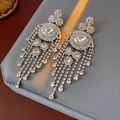 Dettaglio di orecchini vintage in argento con cristalli e nappe su velluto grigio - Argento