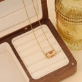 Gold stainless steel necklace with eye pendant displayed in a wooden jewelry box - Red