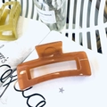 Detail of a large amber caramel rectangle hollow hair claw clip on a white shelf - 12.5CM / Translucent Dark Orange