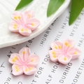 Macro detail of three pink resin cherry blossom DIY charms with yellow centers - Light Pink