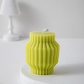 Modern light green geometric candle with vertical ribs on a white display pedestal - Yellow & Green