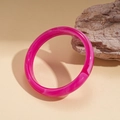 Detalle de brazalete de resina rosa jaspeada apoyado contra una piedra natural - Rosa