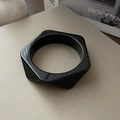 Vista macro de un brazalete hexagonal de resina negra gruesa con acabado pulido - Negro