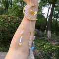 Macro shot of gold wire moon pendant filled with pink quartz and prism crystal suncatcher - Rose Quartz