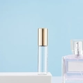 Compact clear glass essential oil roller bottle with elegant gold metal cap and blue background - 5ml Gold