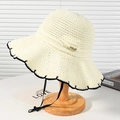 Beige crochet straw sun hat with black scalloped trim and bow on wooden stand - White Wavy Edge