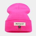 Détail du bonnet en maille rose vif avec anneau métallique et écusson brodé - Taille unique / Rose rouge