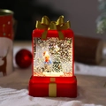 Detail van warme LED-kerstsneeuwbal in rode geschenkdoosvorm met gouden glitters - Kleine Jongen Stijl