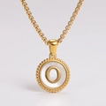 Macro shot of gold pendant with white shell inlay and 3D letter O on metal chain - Letter O