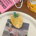 Detalle de una creativa pinza para el cabello con forma de vegetal y textura de acetato - Pimiento amarillo