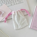 Detailed close-up of a white polka dot drawstring pouch on a laptop with a pink cord - Peach Pink Rope