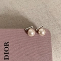 Makro-Detail eleganter Perlenohrstecker mit Silberstäben auf weichem Stoffhintergrund - Silber Weiß Glanzperle