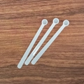 Three white plastic measuring spoons with long handles on a rustic wooden table surface - 0.25ml Long Handle (9.5*1*0.6cm) / White