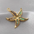Golden starfish pendant with iridescent shell inlay on a grey velvet background - Iridescent Starfish